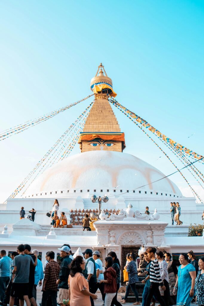 Tourists exploring the iconic Boudhanath Stupa in Kathmandu, Nepal on a sunny day.